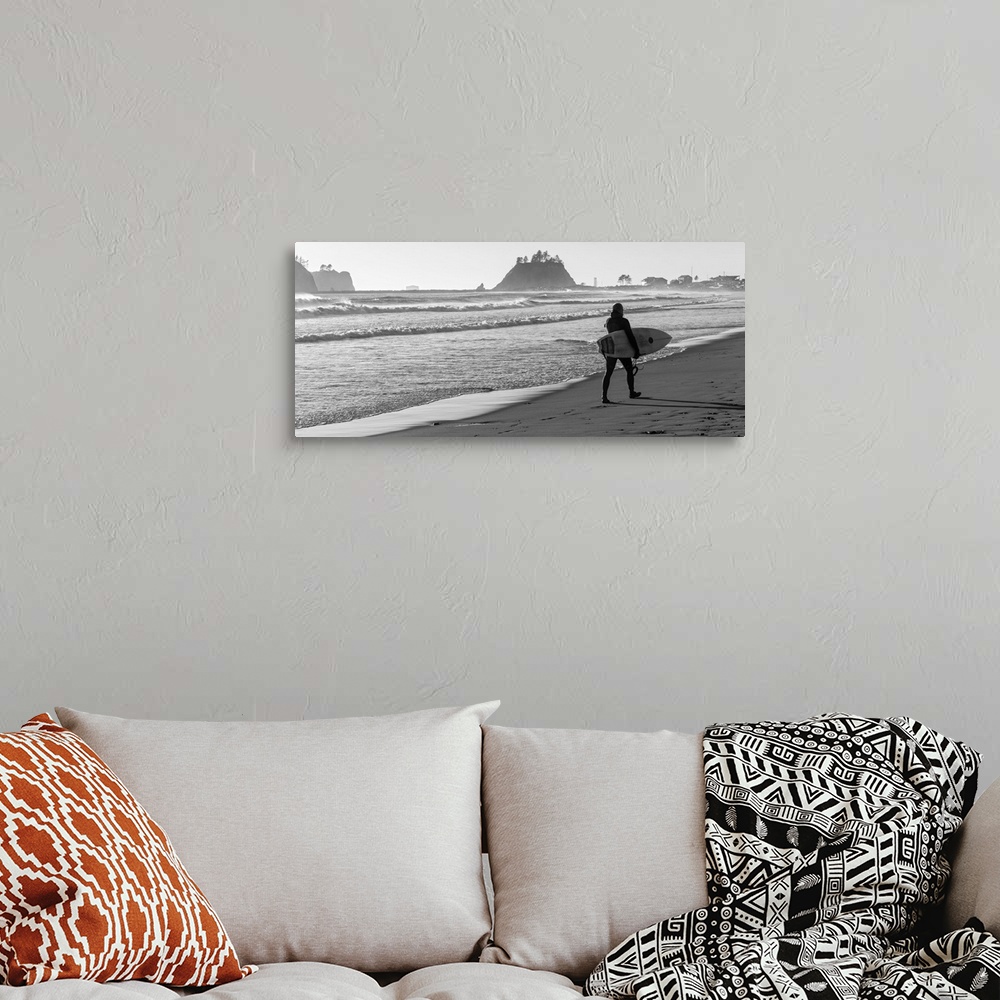 A bohemian room featuring Black and white panoramic photograph of a surfer walking along the shore at La Push Beach in Wash...
