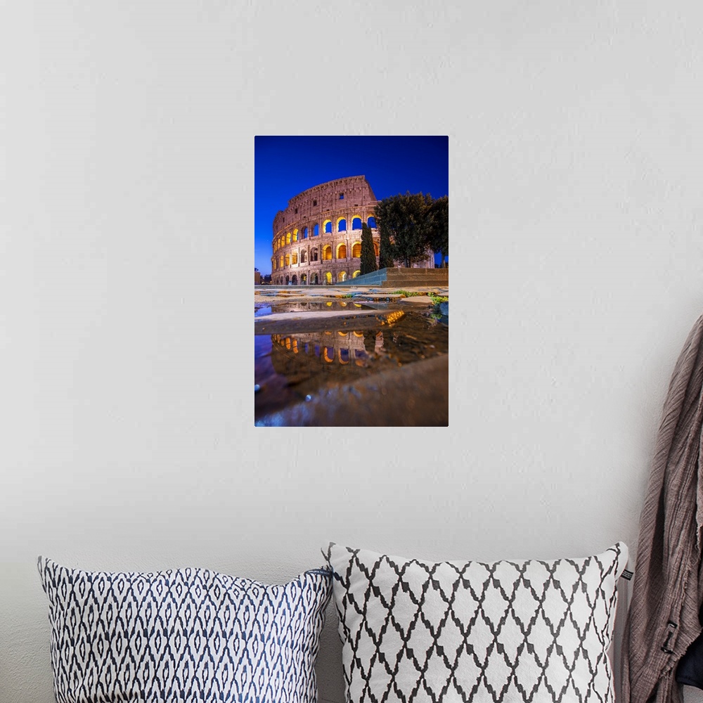 A bohemian room featuring Photograph of the Colosseum at night reflecting into a puddle on the ground.