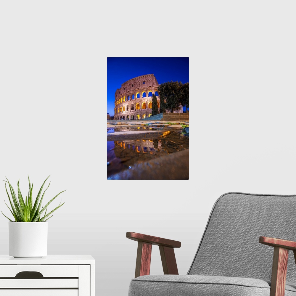 A modern room featuring Photograph of the Colosseum at night reflecting into a puddle on the ground.