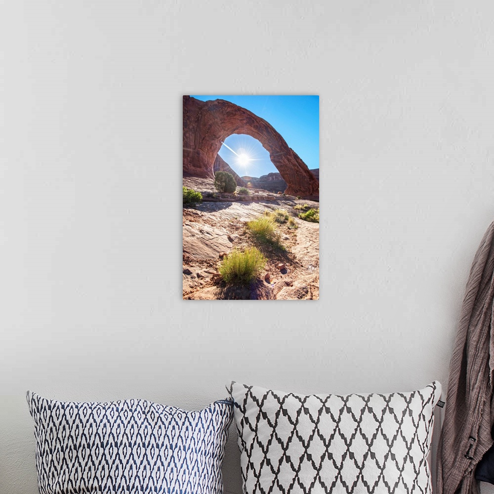 A bohemian room featuring The sun framed by the Corona Arch under a blue sky in Arches National Park, Utah.