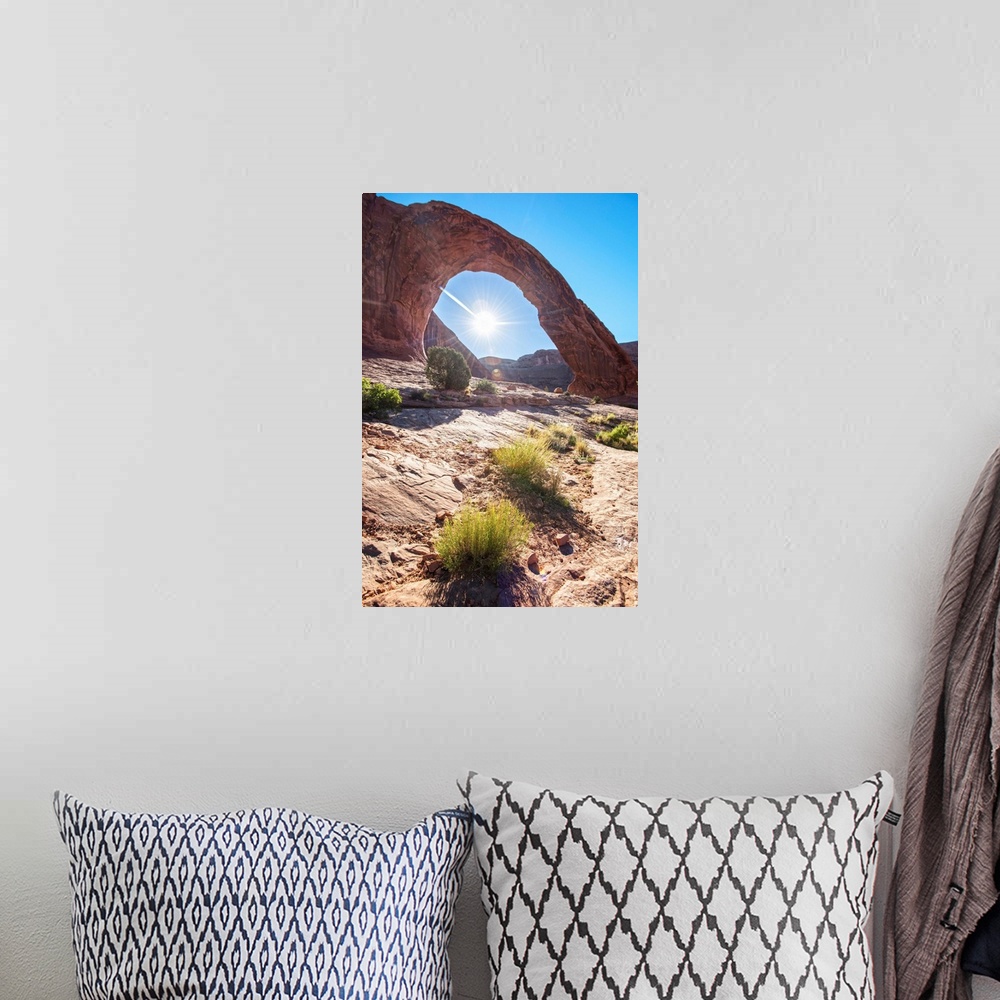 A bohemian room featuring The sun framed by the Corona Arch under a blue sky in Arches National Park, Utah.