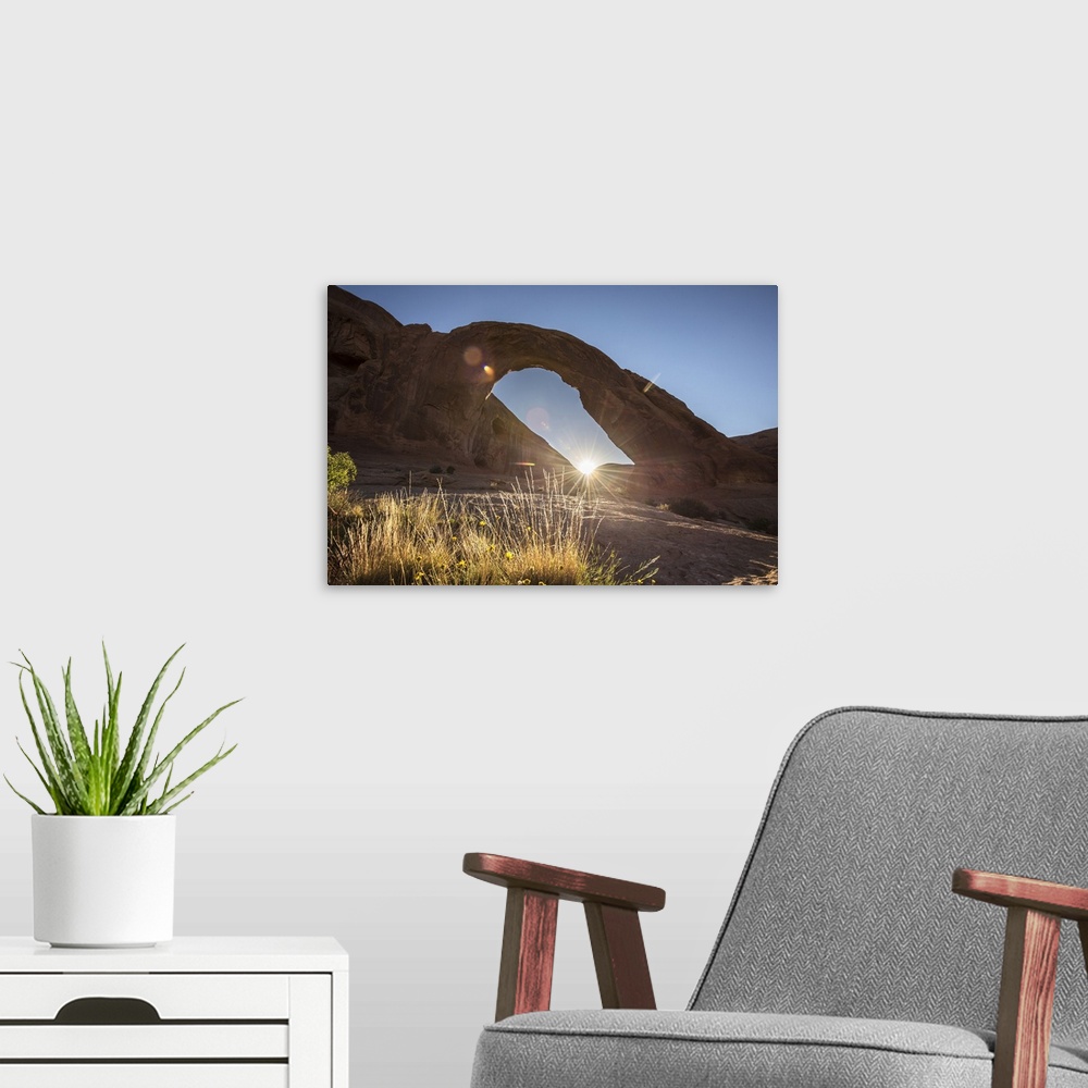 A modern room featuring The sun peeking behind the Corona Arch illuminating the desert grasses in Arches National Park, U...