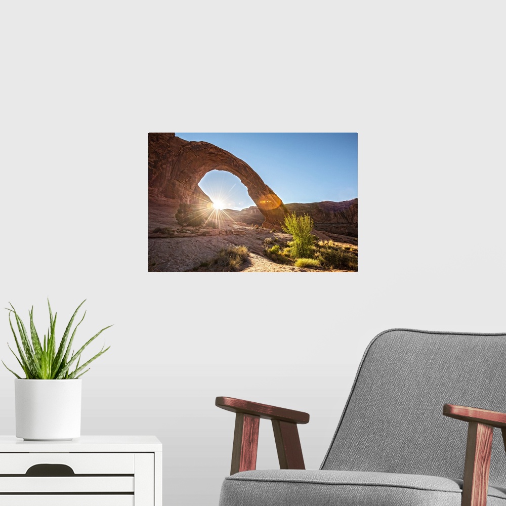 A modern room featuring The sun peeking behind the Corona Arch illuminating the desert grasses in Arches National Park, U...