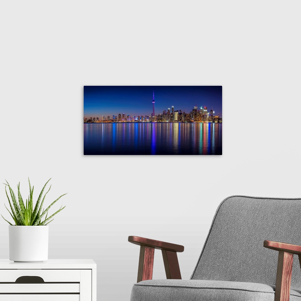 A modern room featuring Photo of the Toronto city skyline with lights reflected in the water at night.