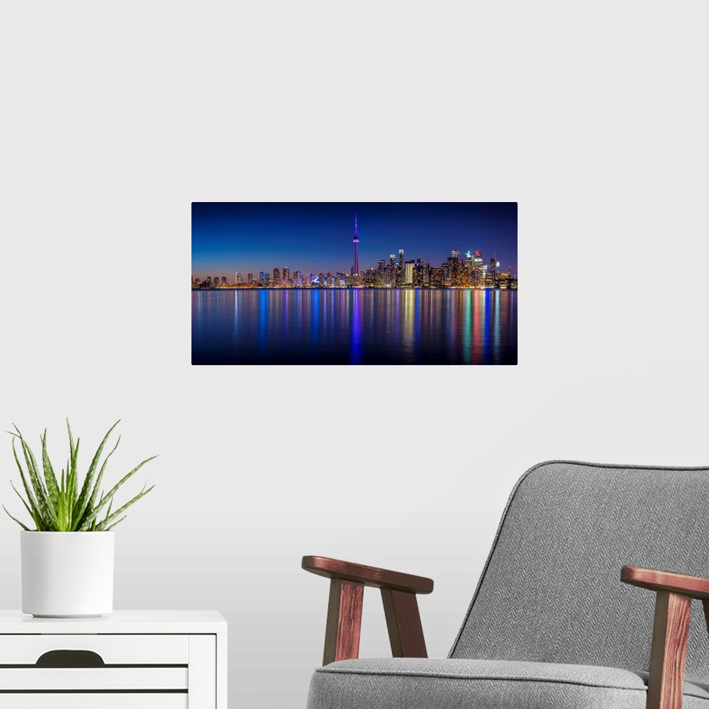 A modern room featuring Photo of the Toronto city skyline with lights reflected in the water at night.