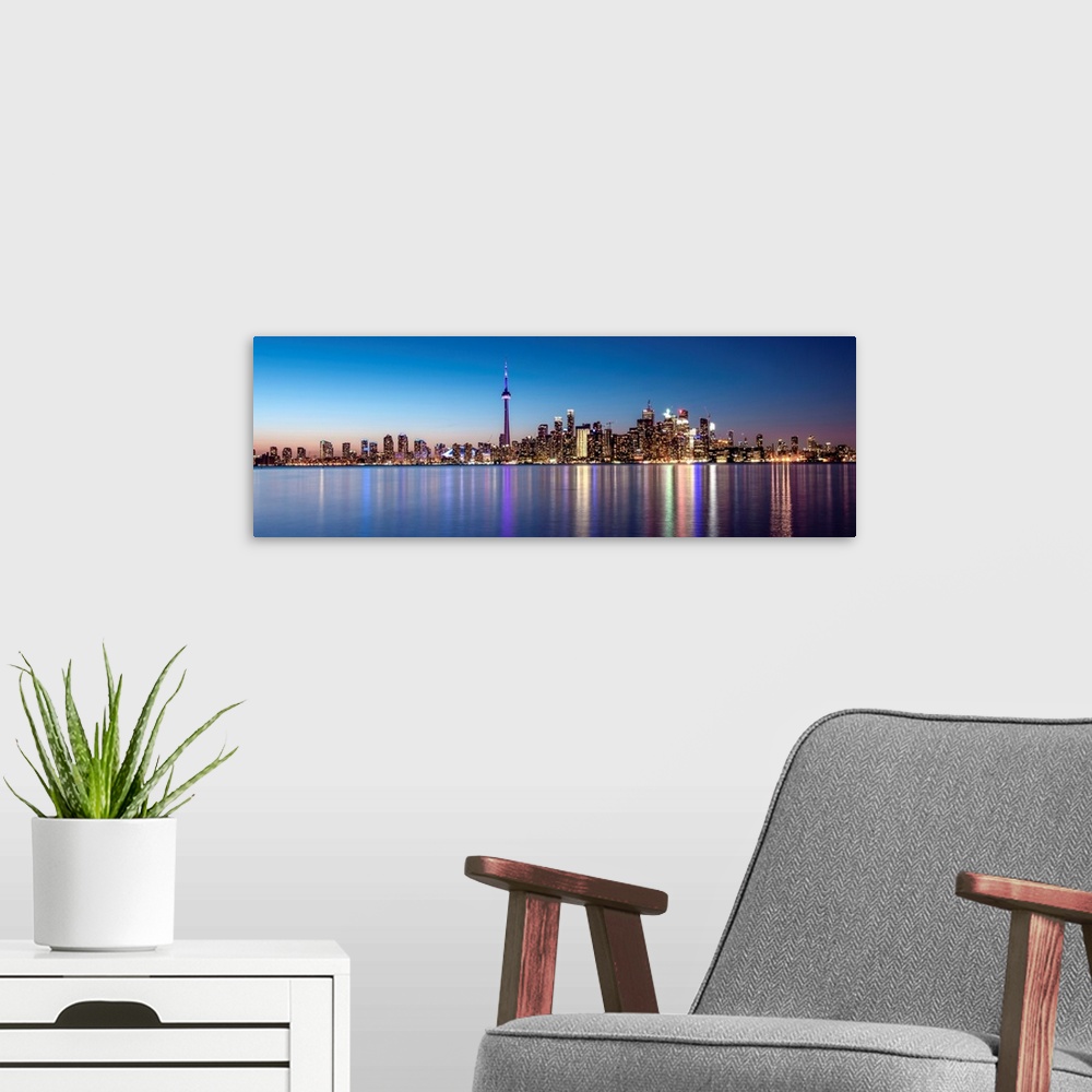 A modern room featuring Panoramic photo of the Toronto city skyline with lights reflected in the water at night.