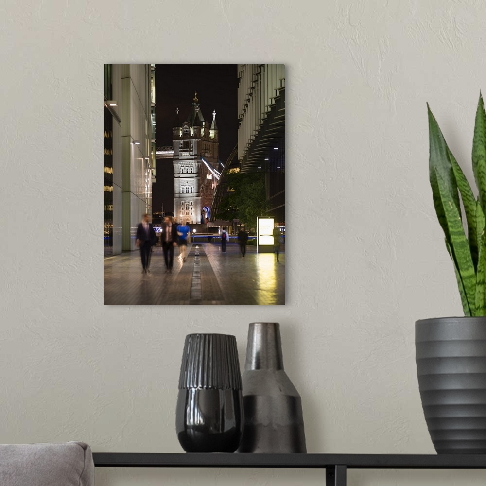A modern room featuring Photograph of one of the two towers on Tower Bridge seen through a London cityscape at night.
