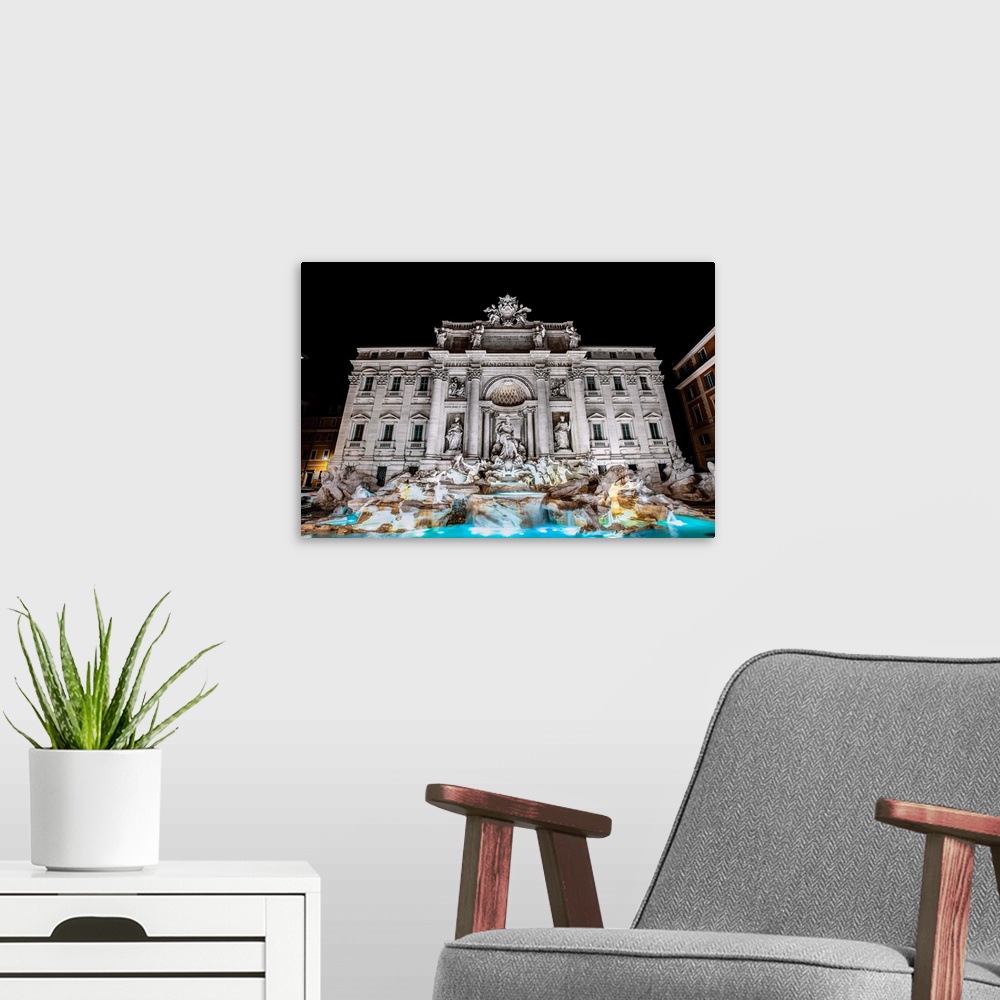 A modern room featuring Photograph of the Trevi Fountain in the Trevi district in Rome, Italy, at night.