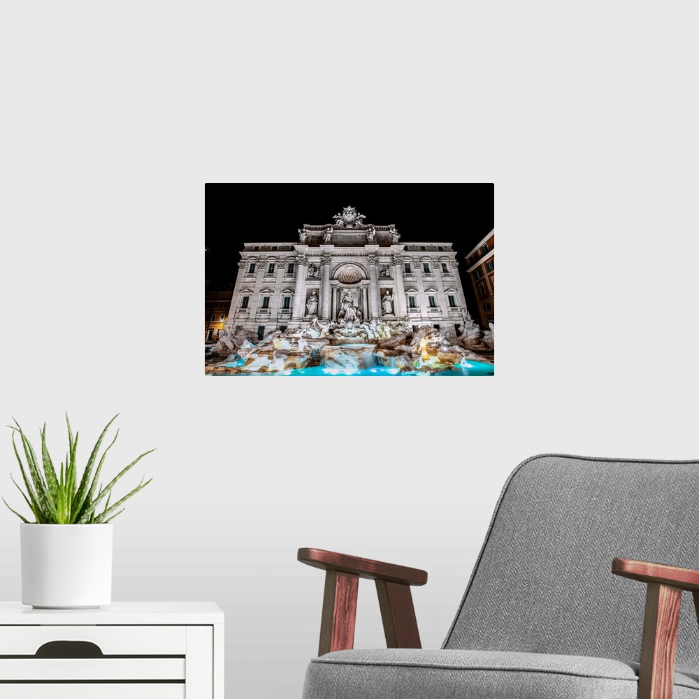 A modern room featuring Photograph of the Trevi Fountain in the Trevi district in Rome, Italy, at night.