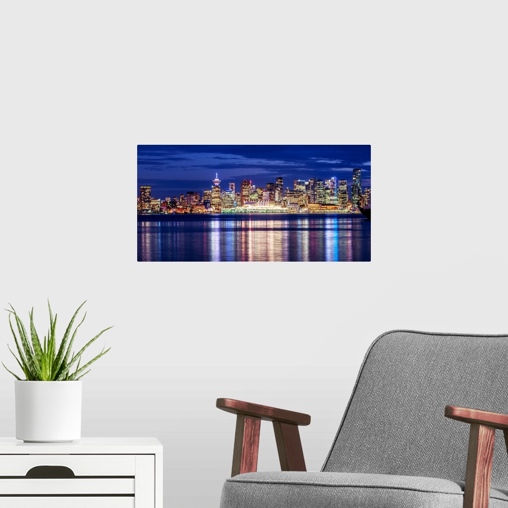 A modern room featuring Photograph of the Vancouver, British Columbia skyline lit up on a dark blue night and reflecting ...