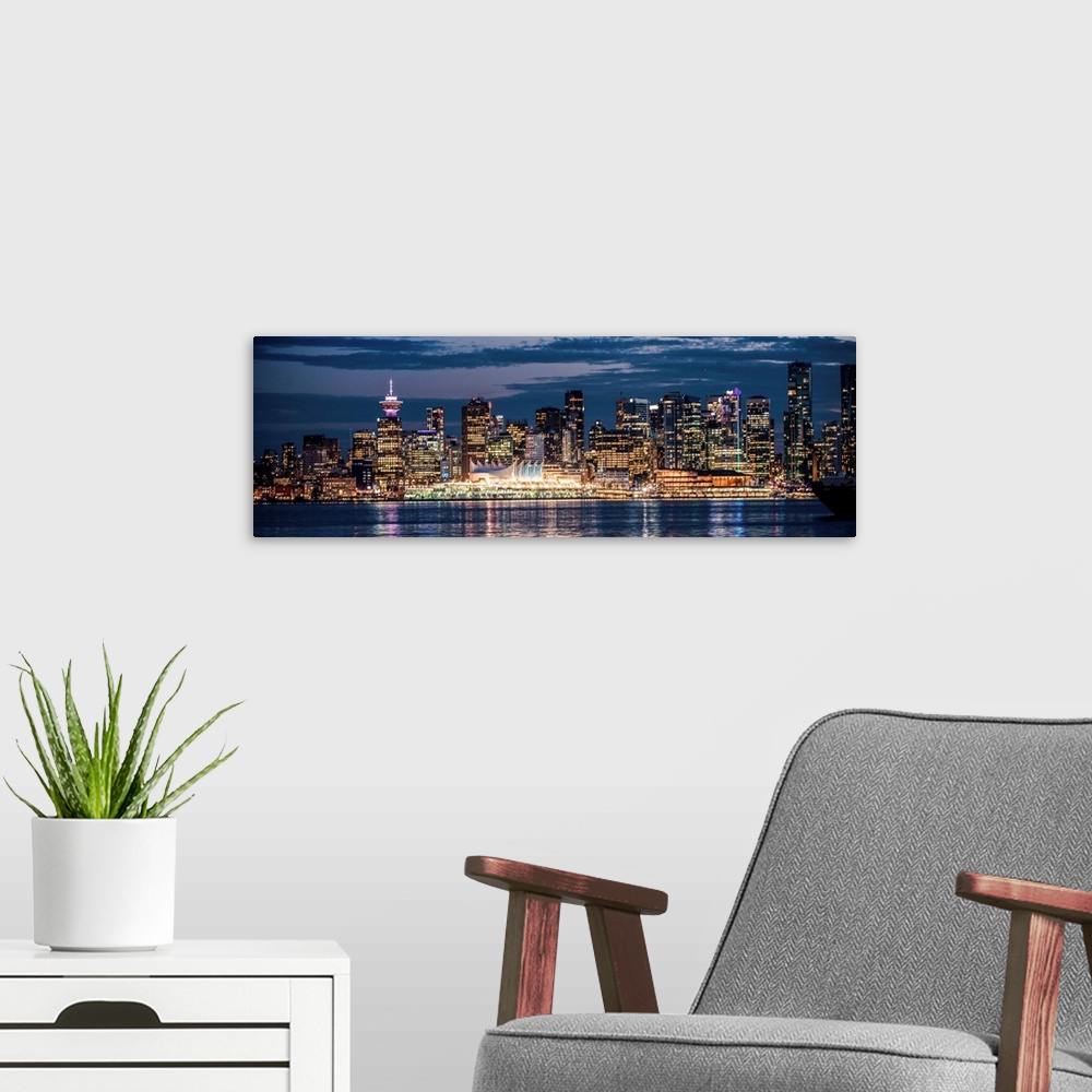 A modern room featuring Panoramic photograph of the Vancouver, British Columbia skyline lit up on a dark blue night and r...