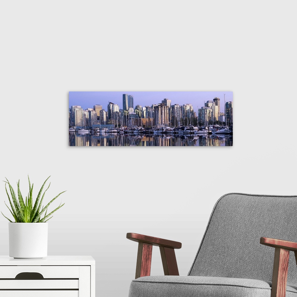 A modern room featuring Panoramic photograph of a purple sunset over the Vancouver skyline and harbor reflecting onto the...
