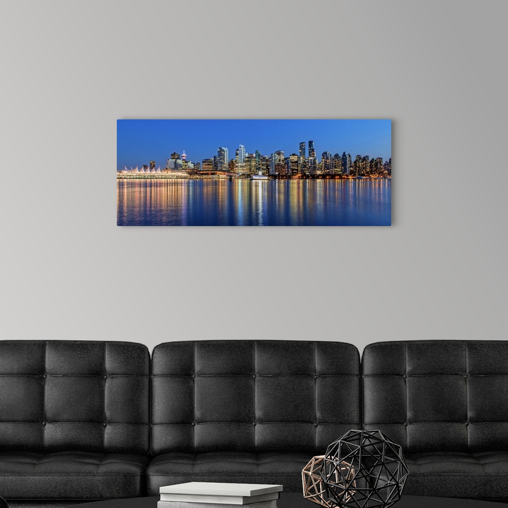 A modern room featuring Photograph of the downtown Vancouver skyline lit up at dusk and reflecting onto the water creatin...