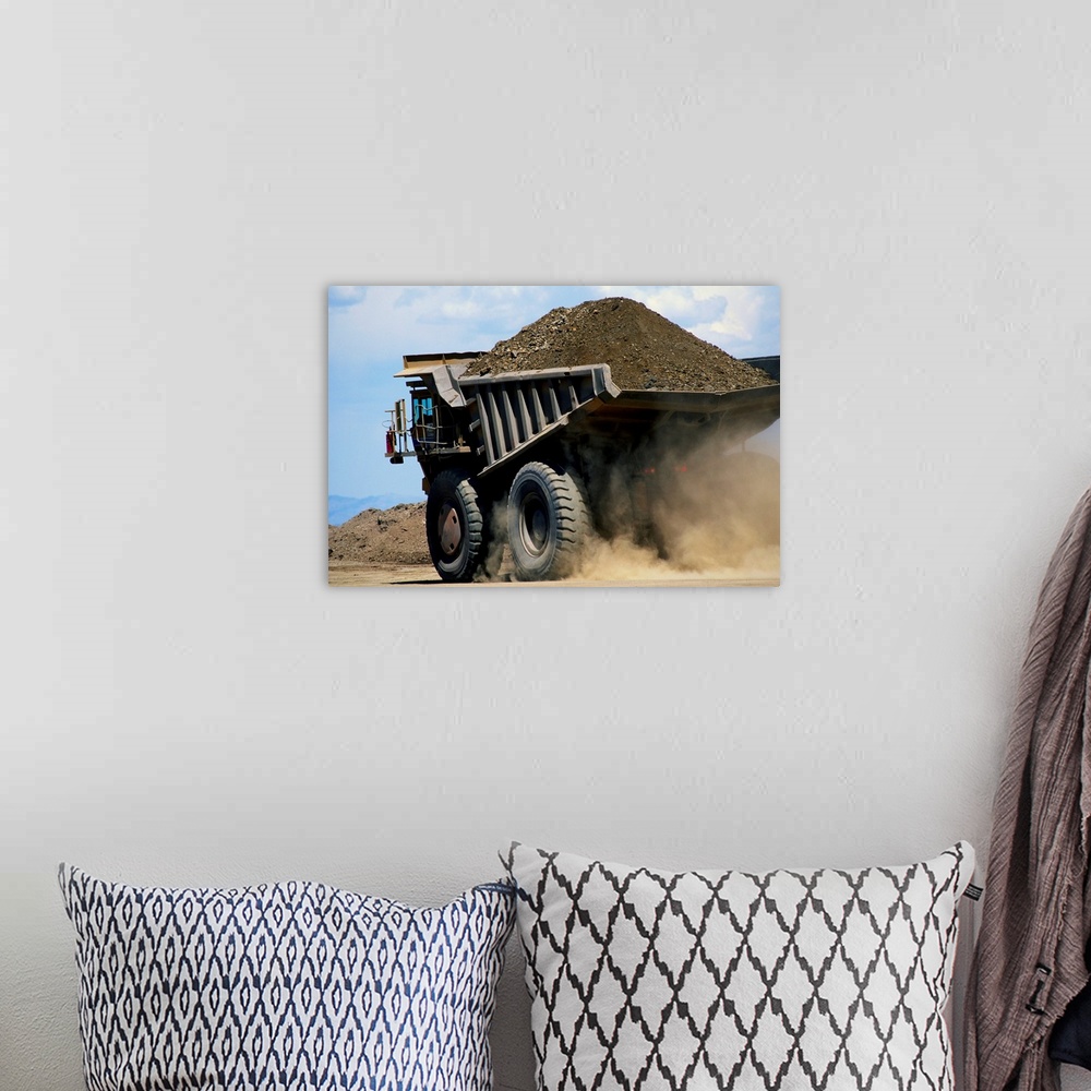 A bohemian room featuring A dump truck carrying gravel kicks up a cloud of dust.