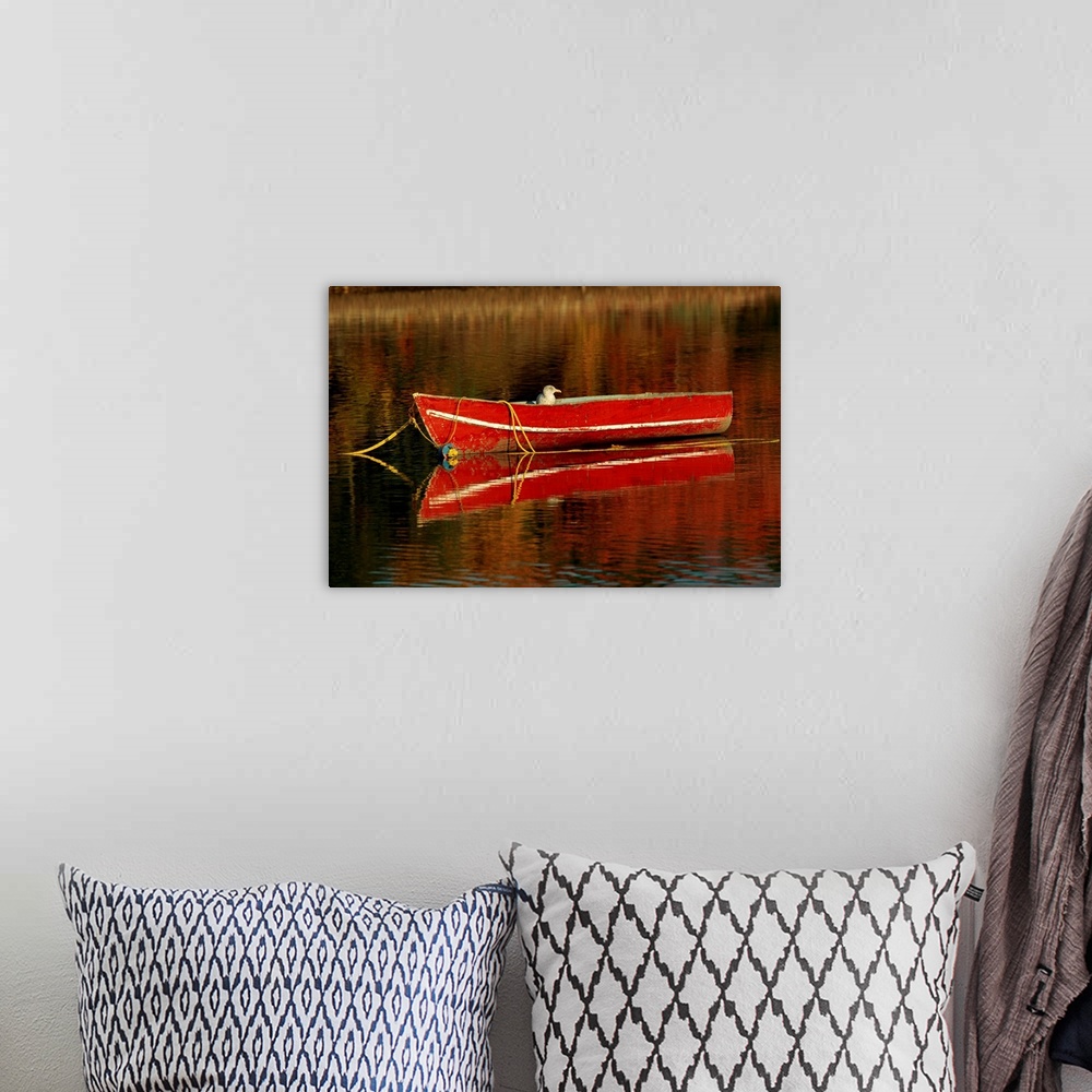A bohemian room featuring A moored old red boat and its mirror reflection on still waters.