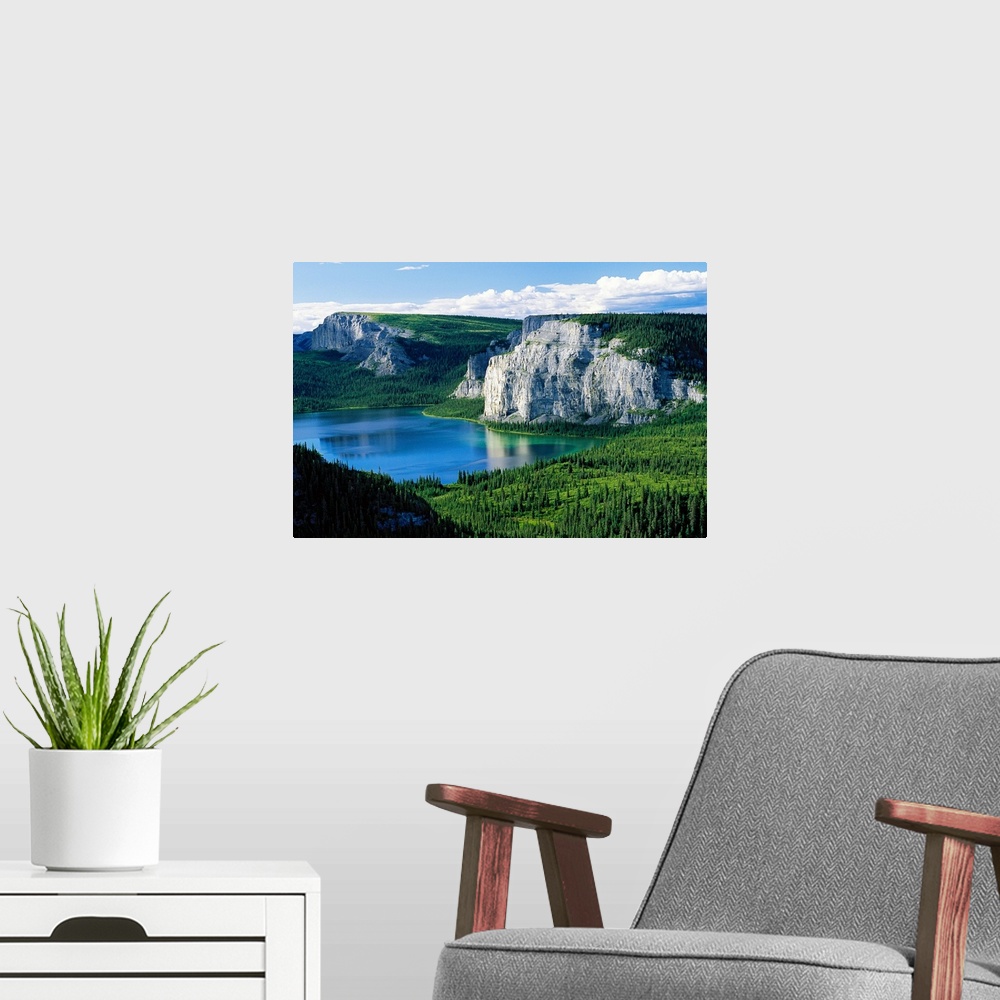 A modern room featuring Photograph taken of immense cliffs known as Death Lake. The land is blanketed with trees and the ...