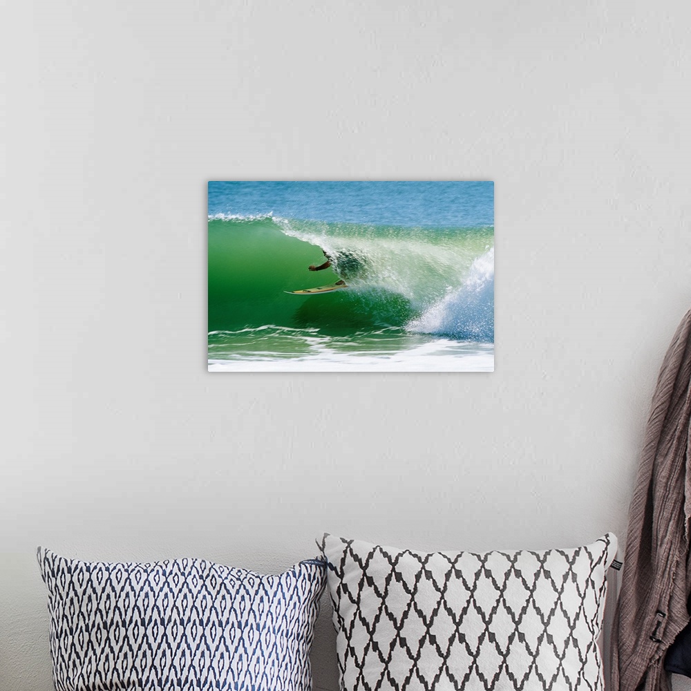 A bohemian room featuring From the National Geographic Collection a landscape photograph of a surfer passing through a barr...