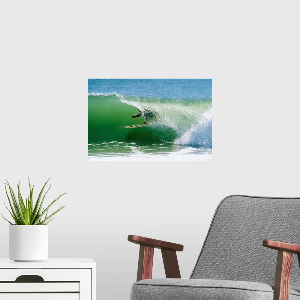 A modern room featuring From the National Geographic Collection a landscape photograph of a surfer passing through a barr...