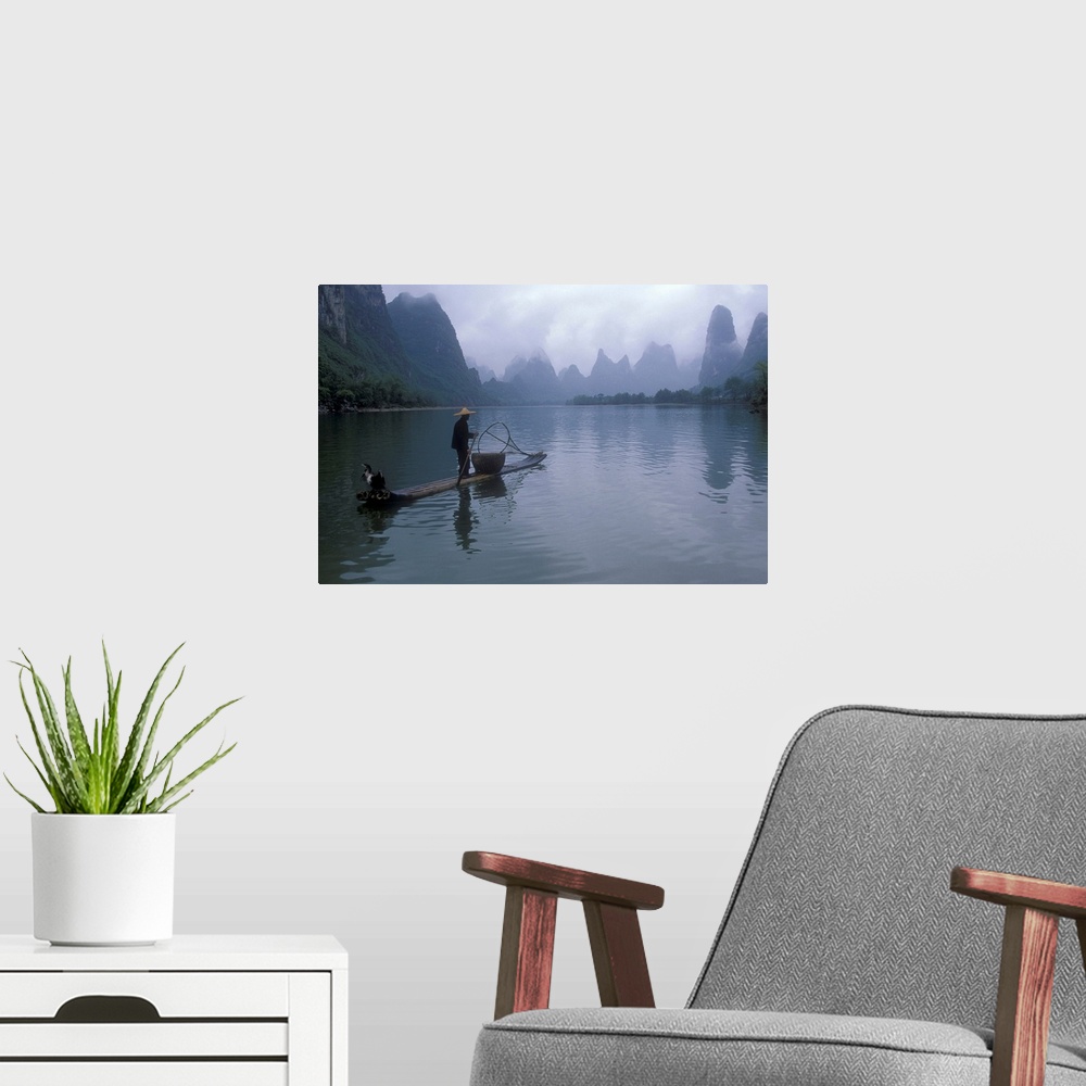 A modern room featuring A fisherman is photographed paddling his raft toward immense cliffs that are shown through a laye...