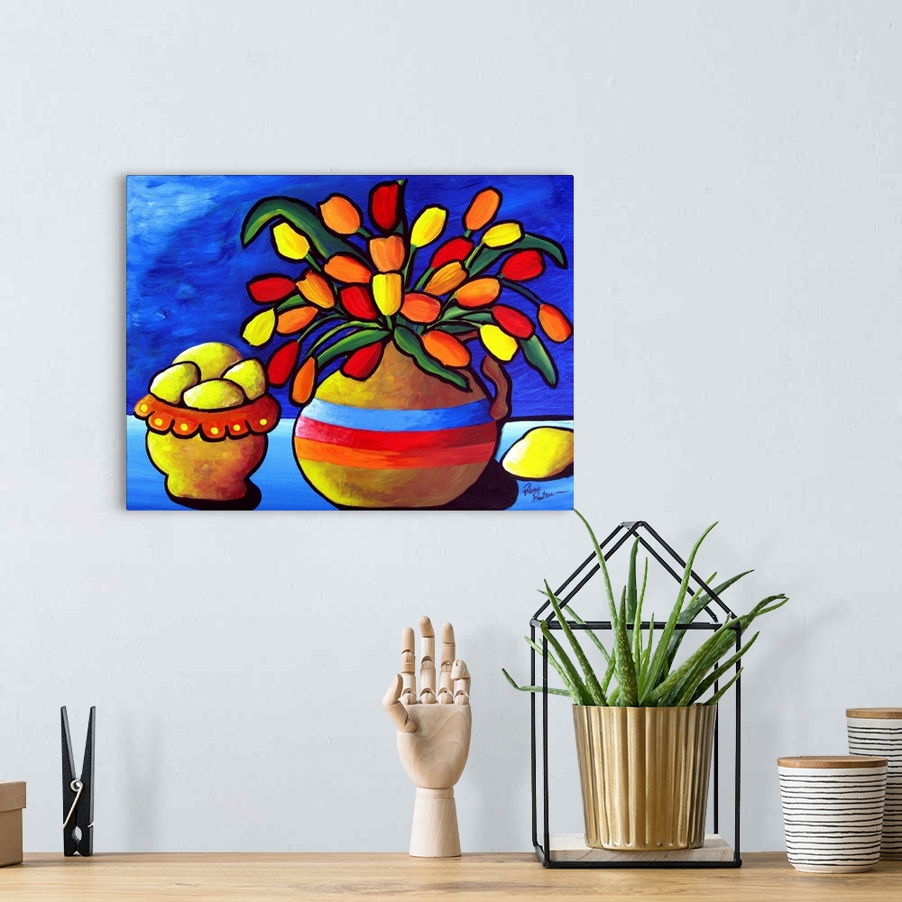 A bohemian room featuring Brightly colored tulips in a vase sit beside a bowl of lemons, against deep blue background
