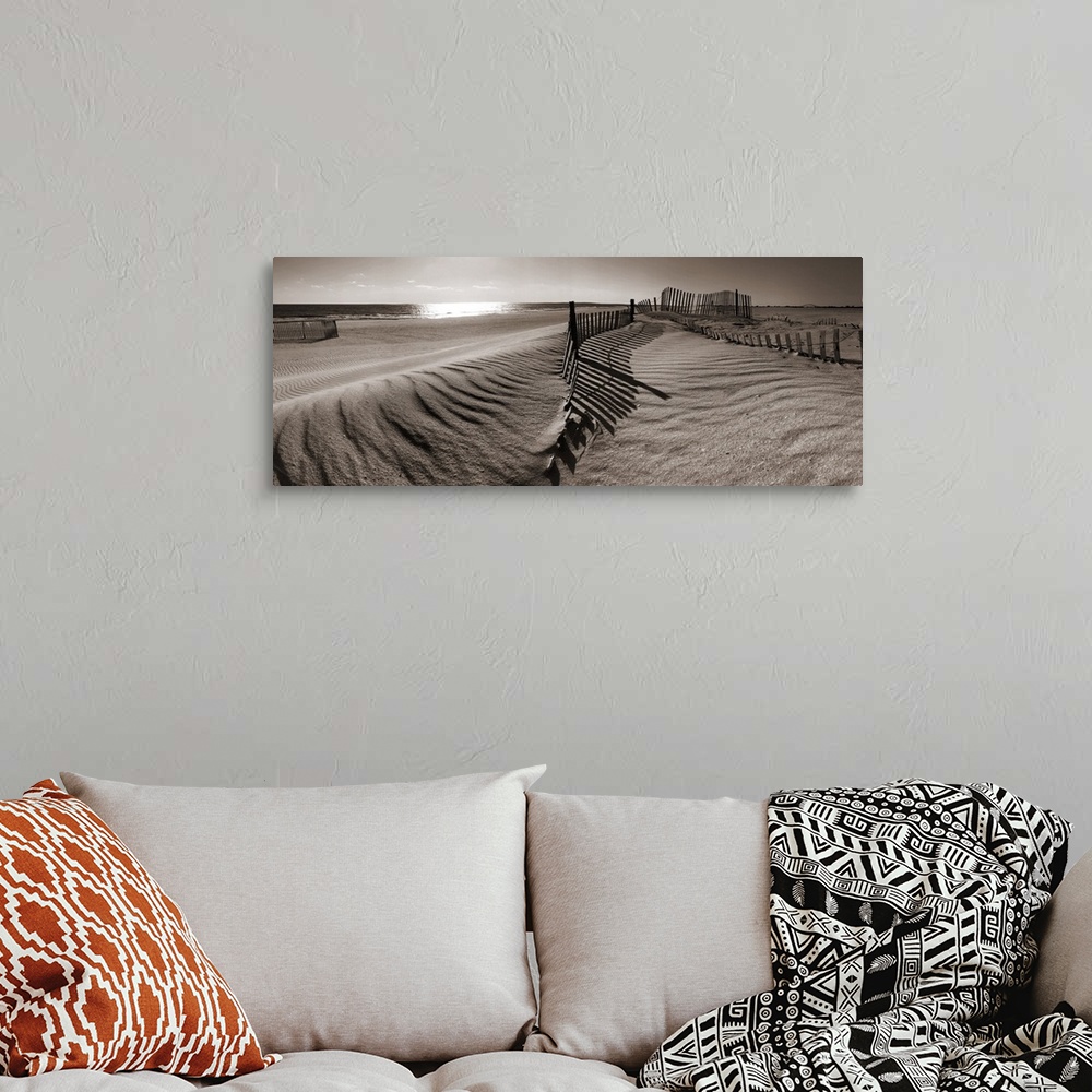 A bohemian room featuring A panoramic landscape of sand dunes on a beach in sepia tones.