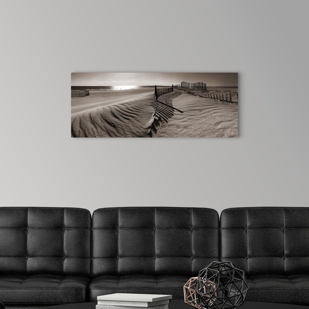 A modern room featuring A panoramic landscape of sand dunes on a beach in sepia tones.
