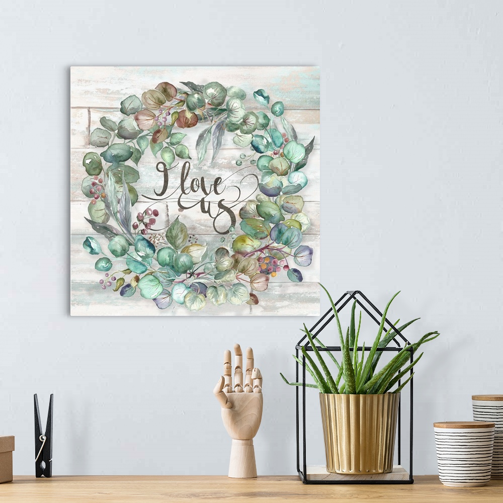 A bohemian room featuring A square decorative watercolor painting of a wreath of succulents and the words 'I love us.'
