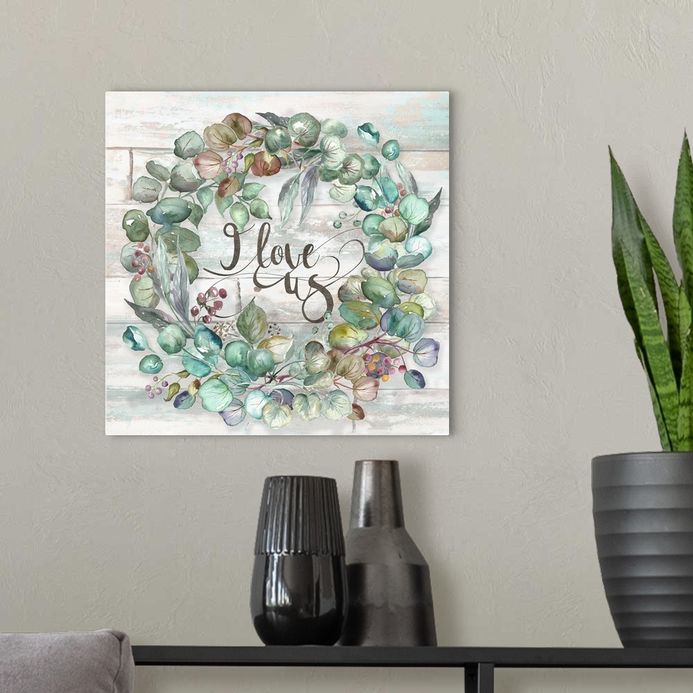 A modern room featuring A square decorative watercolor painting of a wreath of succulents and the words 'I love us.'