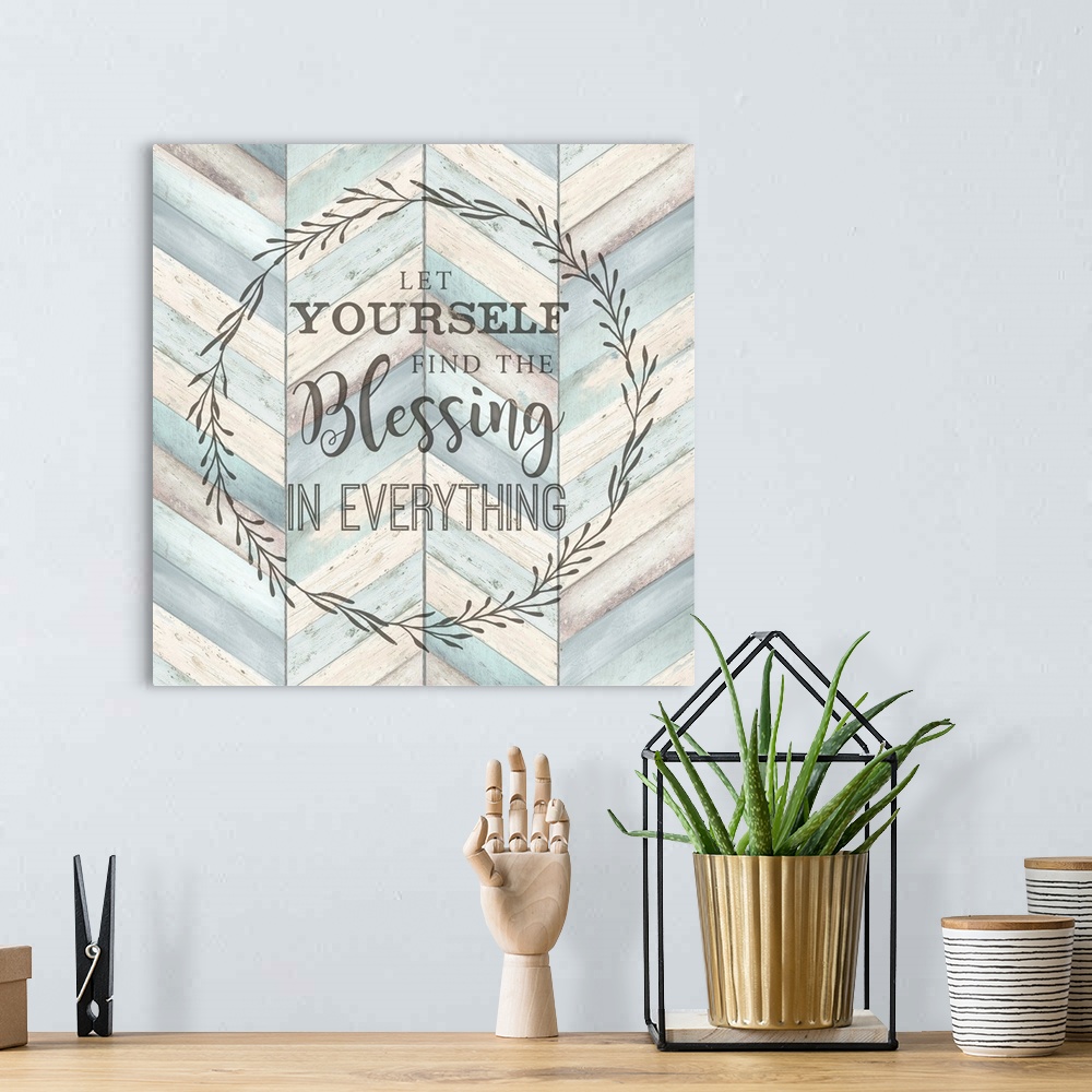 A bohemian room featuring "Let Yourself Find The Blessing In Everything" surround by a wreath on a chevron wood background.