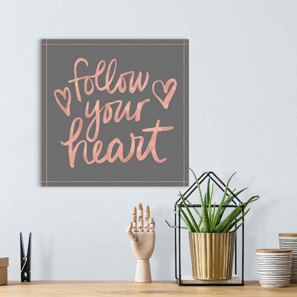 A bohemian room featuring "Follow your heart" in pink with a heart on a gray background.
