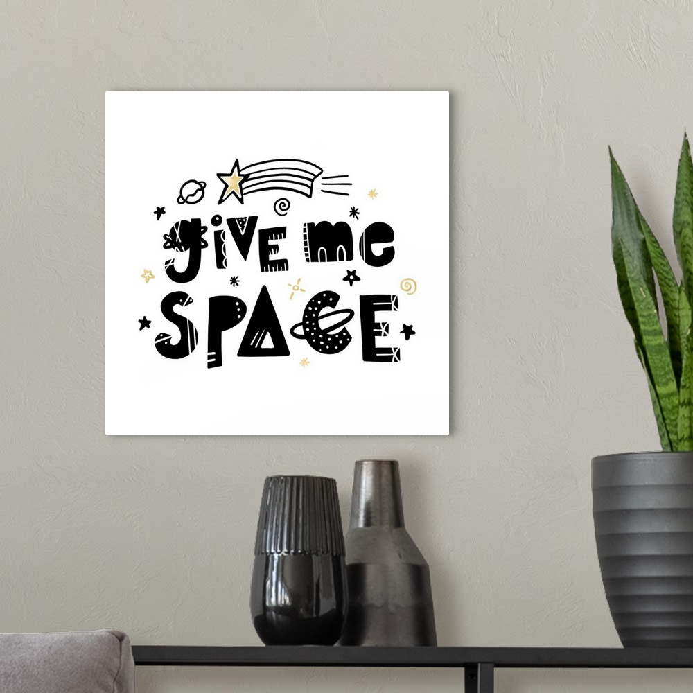 A modern room featuring "Give Me Space" in an artistic font with stars and planets on a white background and gold accents.