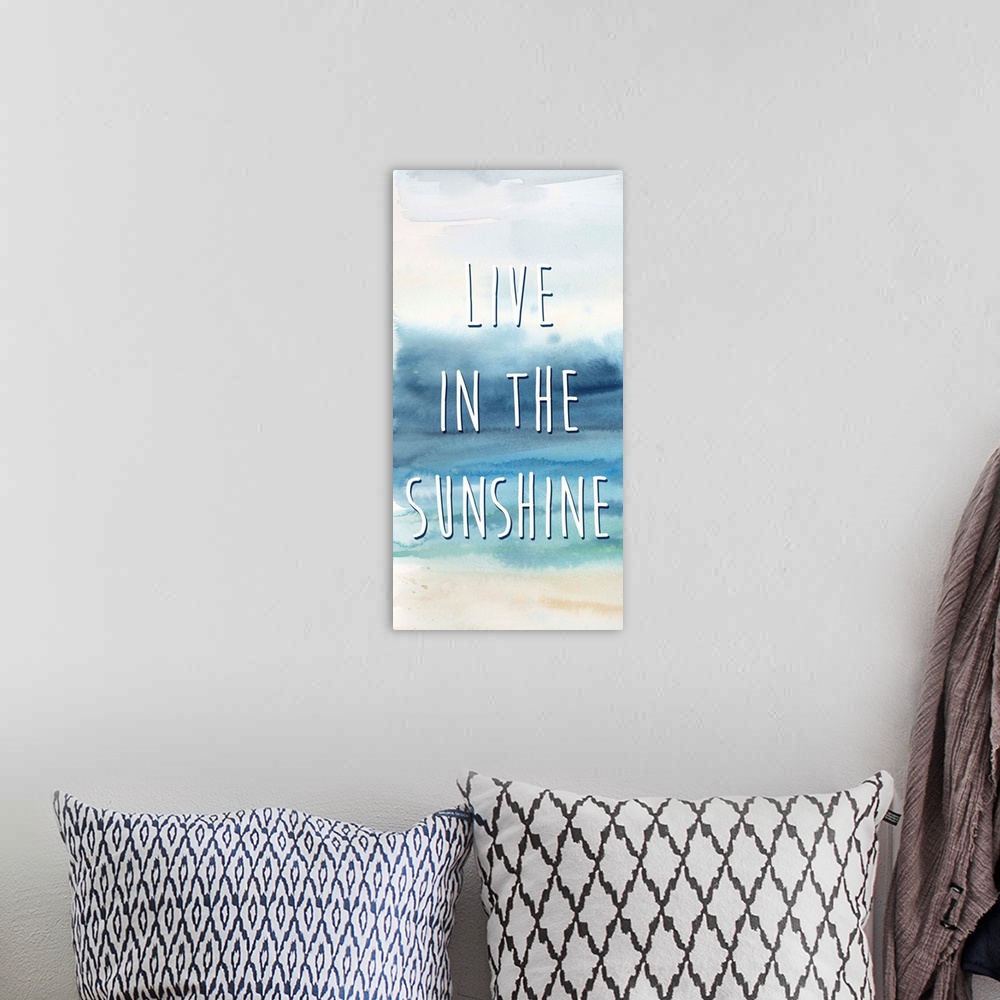 A bohemian room featuring "Live In The Sunshine" in white on a watercolor painting of the ocean.