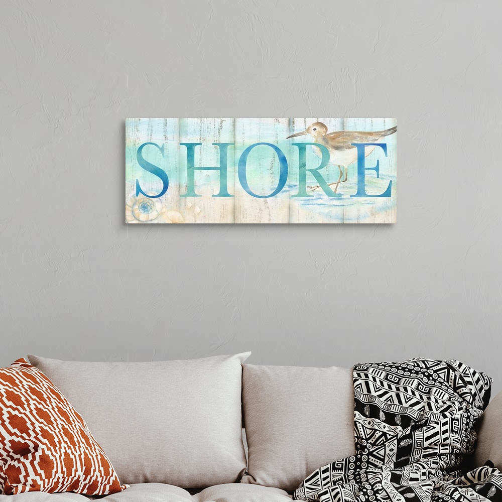 A bohemian room featuring "Shore" in blue over a watercolor image of a shorebird on a beach with a wood plank appearance.
