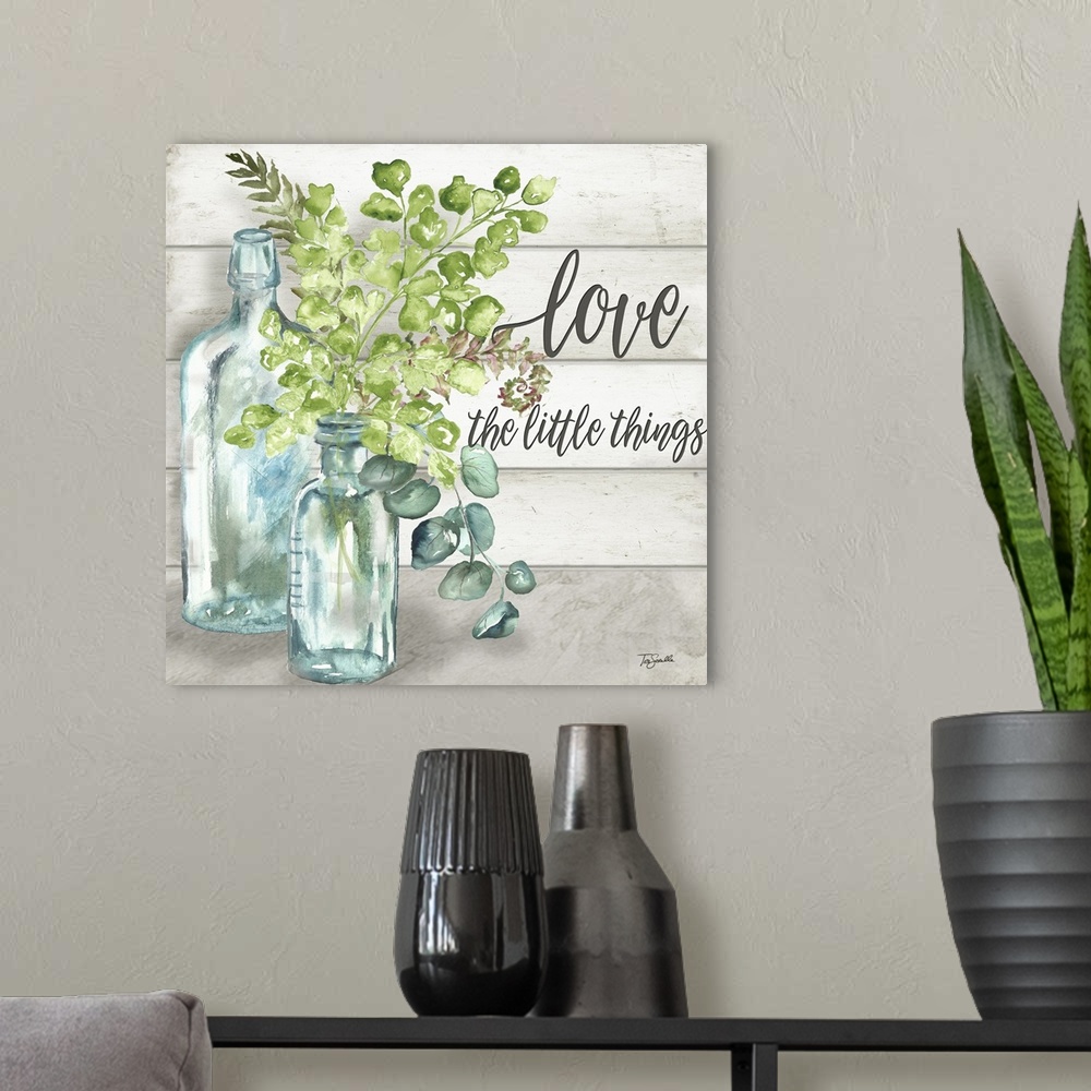 A modern room featuring "Love The Little Things" with glass bottles and greenery on a gray wood panel background.