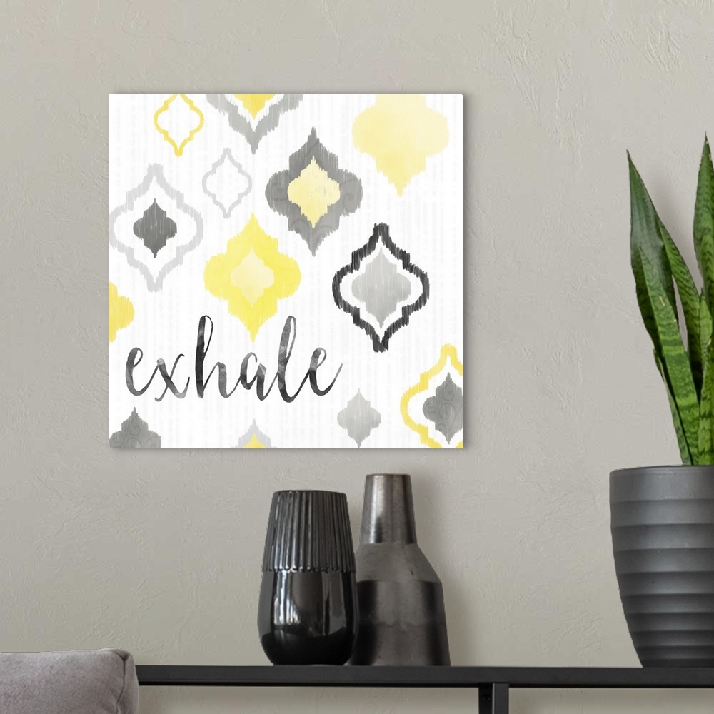 A modern room featuring A square decorative artwork of Moroccan tile designs in yellow and gray with the text 'exhale'.