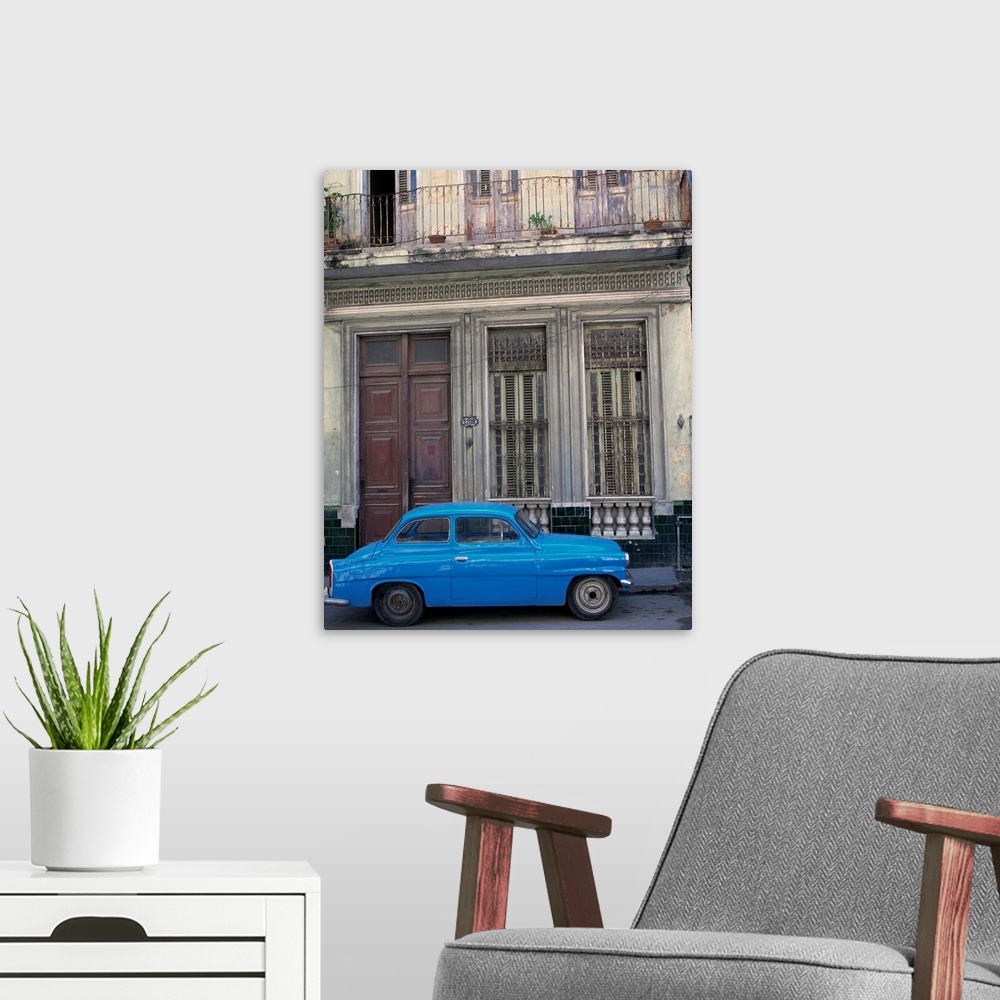 A modern room featuring A blue car parked outside a shabby house in Old Havana, Cuba, West Indies