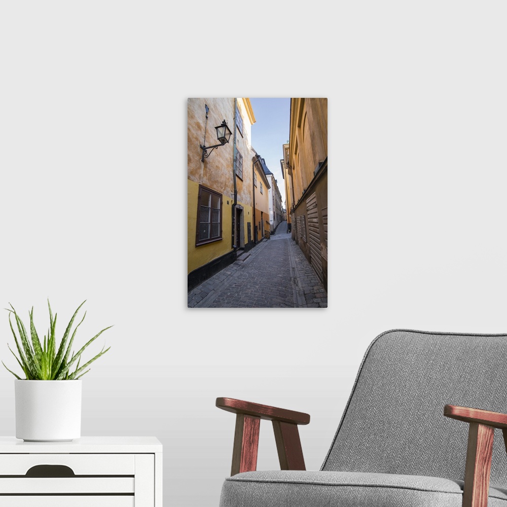 A modern room featuring A pedestrian walks the streets of Stockholm's colorful and historic Gamla Stan district, Stockhol...
