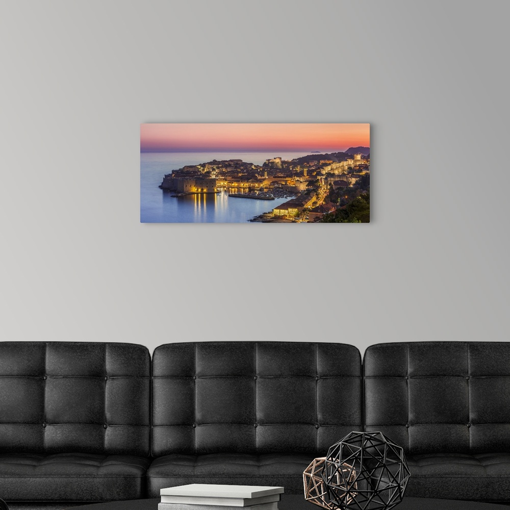 A modern room featuring Aerial panorama of Dubrovnik Old Town at night with orange sunset sky, Dubrovnik, Dalmatian Coast...