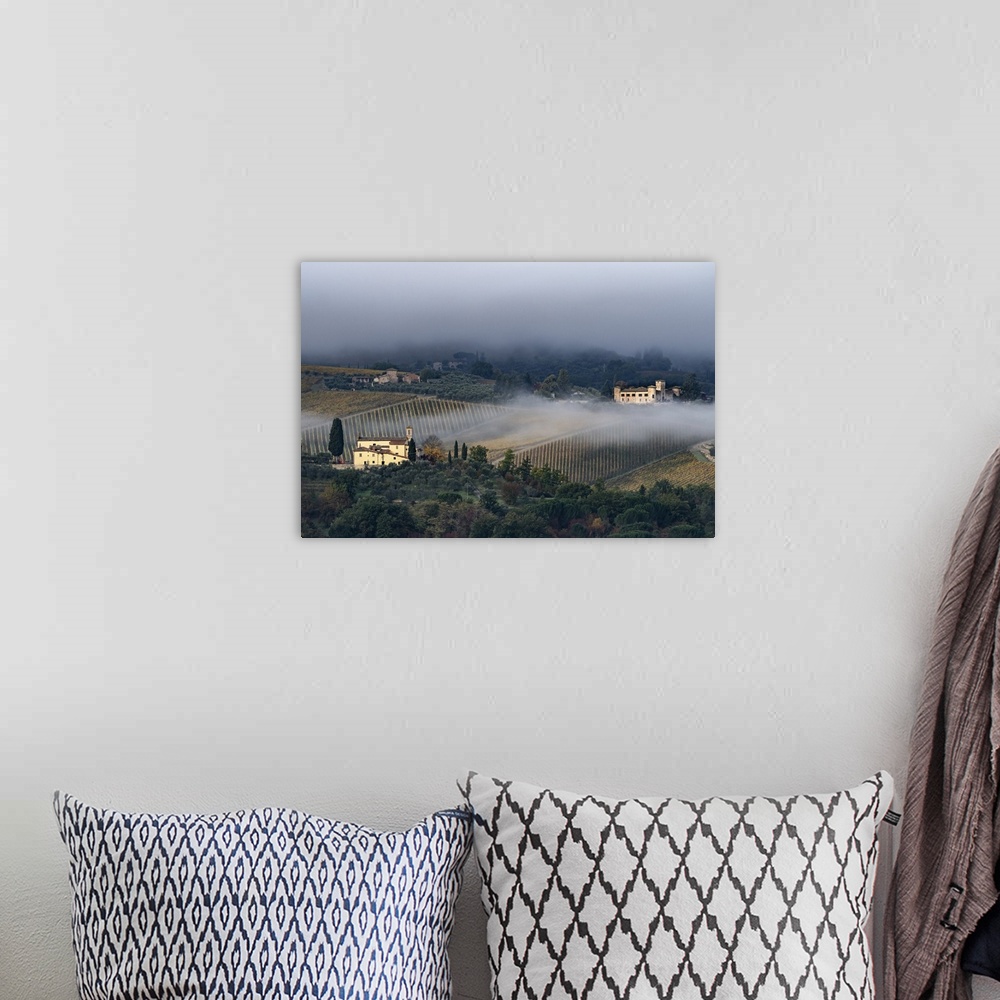 A bohemian room featuring Castello di Gabbiano across a misty valley, church in foreground, San Casciano, Tuscany, Italy, E...