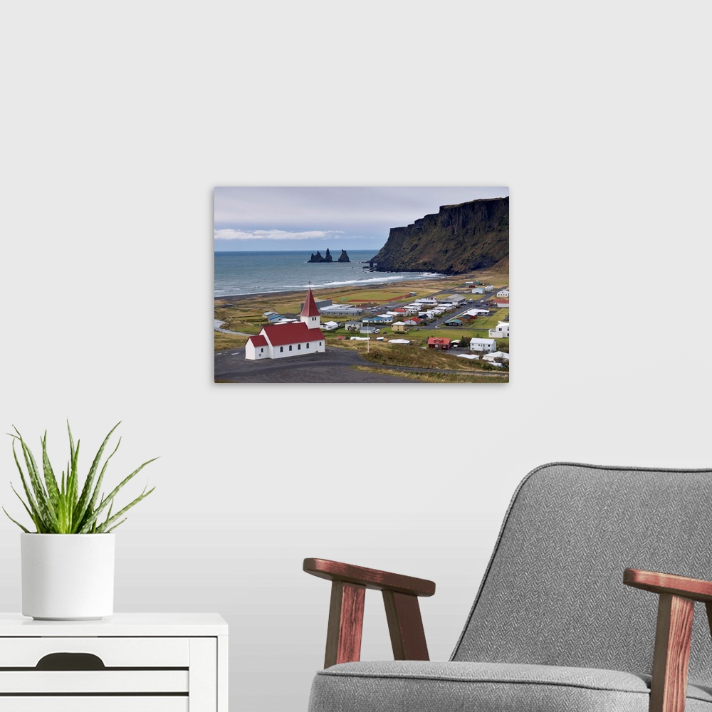 A modern room featuring Church, village of Vik and Reynisdrangar sea stacks in the distance, Iceland