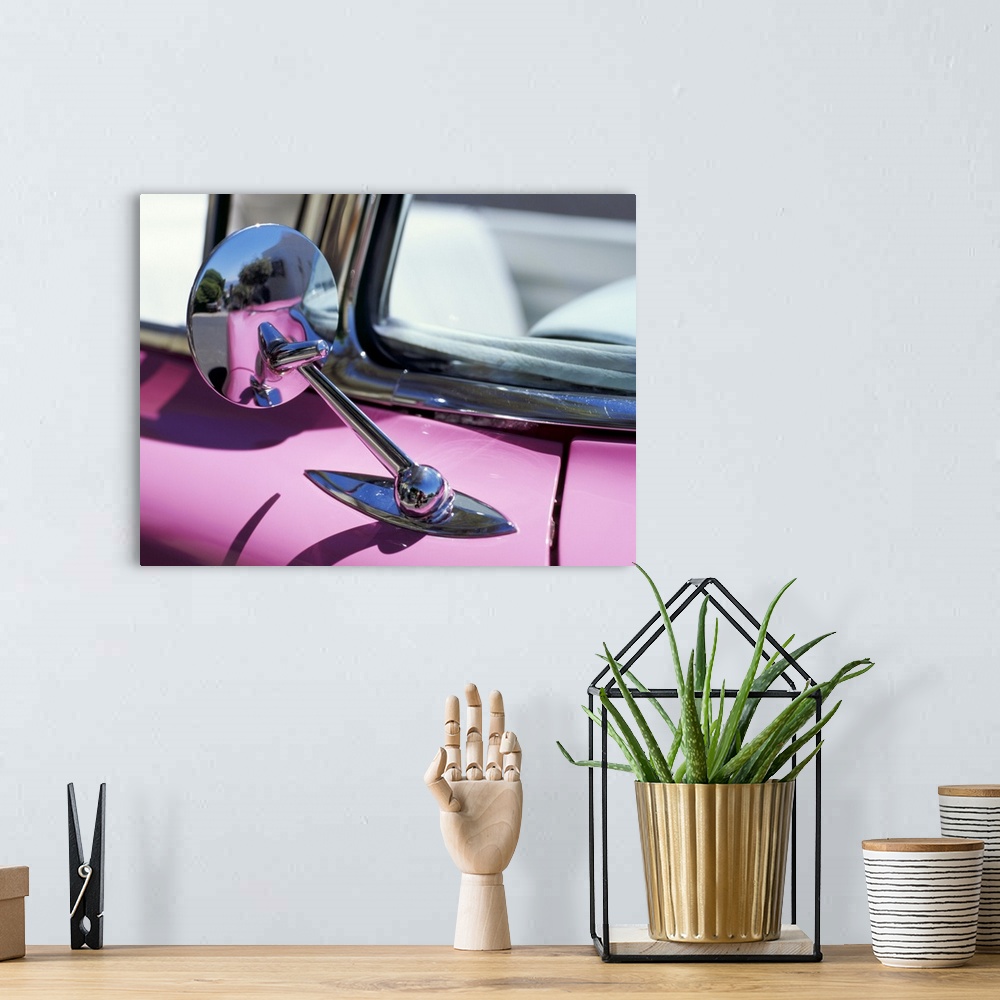 A bohemian room featuring Close-up of a wing mirror and reflection on a pink Cadillac car