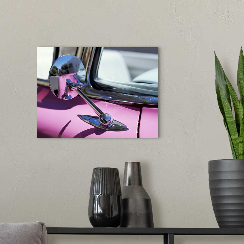 A modern room featuring Close-up of a wing mirror and reflection on a pink Cadillac car
