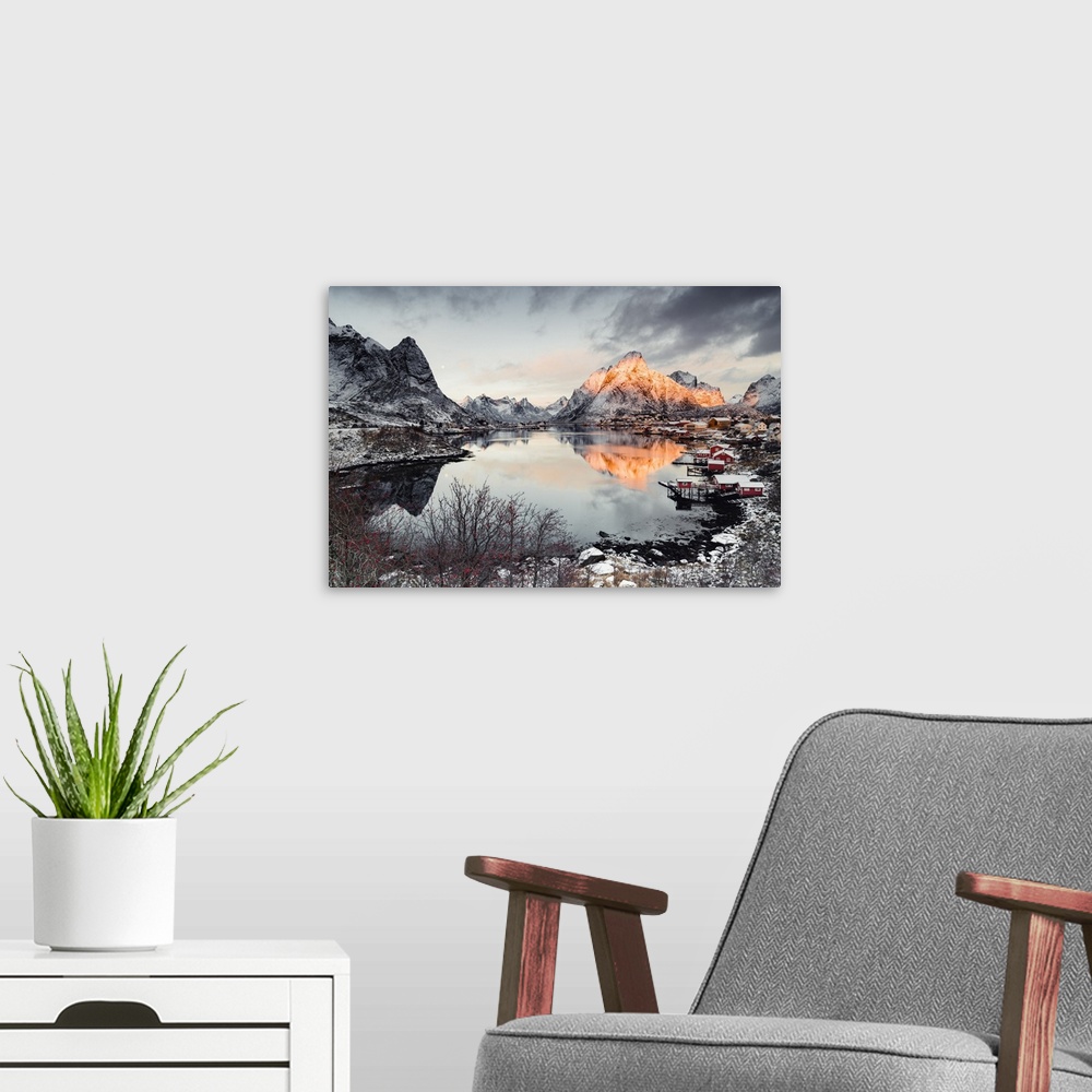 A modern room featuring Clouds at dawn over traditional Rorbu and Olstind mountain reflected in sea, Reine Bay, Nordland,...