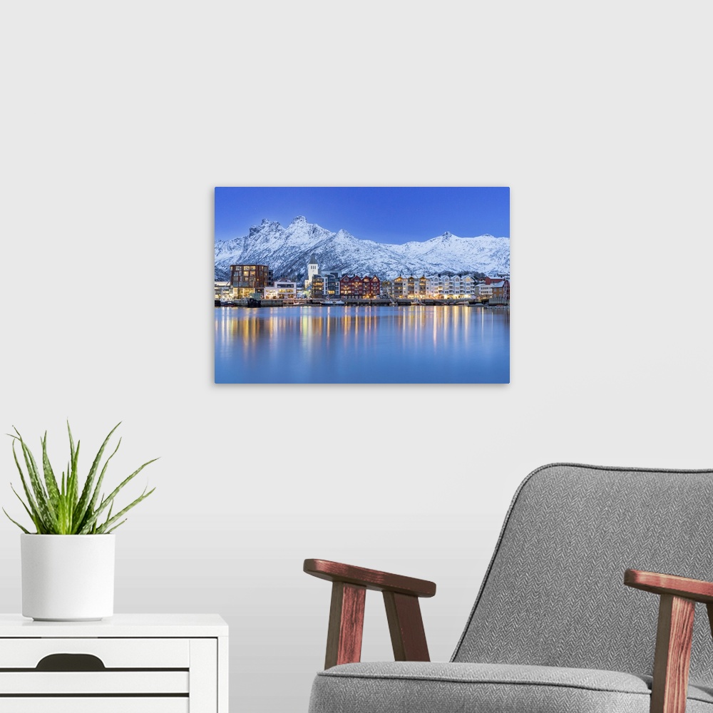 A modern room featuring Coastal town of Svolvaer framed by snowcapped mountains at dusk, Nordland county, Lofoten Islands...