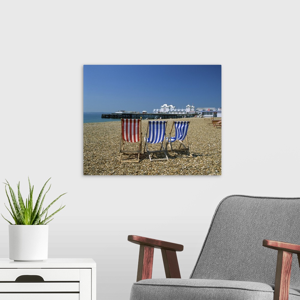 A modern room featuring Empty deck chairs on the beach and the Southsea Pier, Hampshire, England