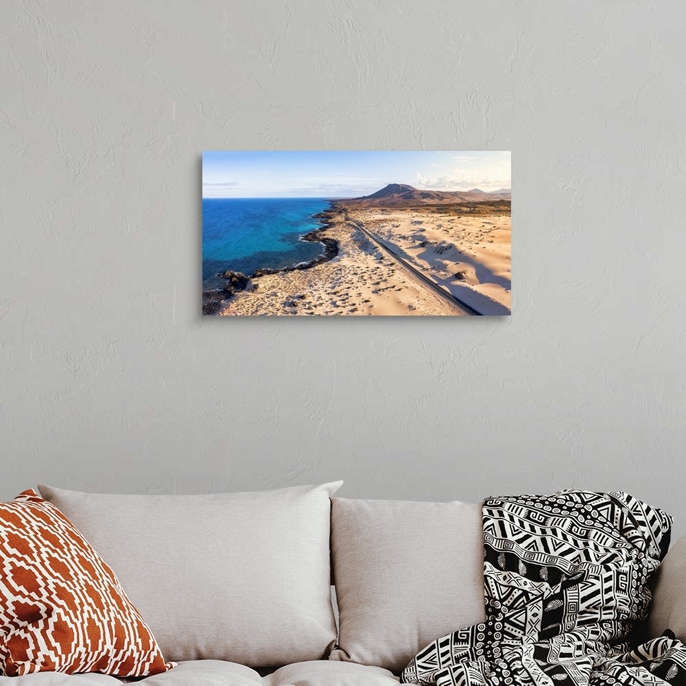 A bohemian room featuring Empty road crossing the sand dunes overlooking the ocean, Corralejo Natural Park, Fuerteventura, ...