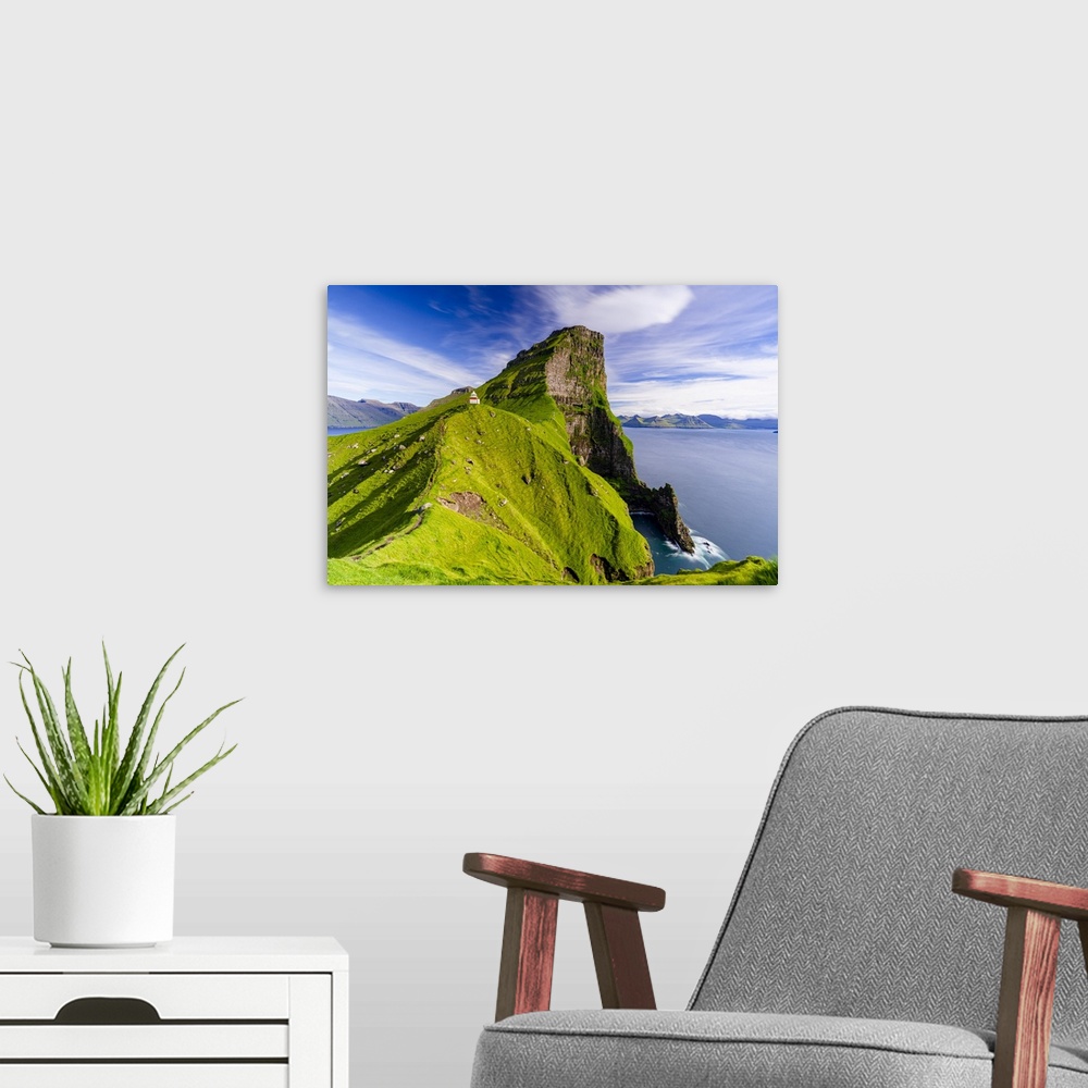 A modern room featuring Kallur lighthouse on cliffs covered with grass with Borgarin mountain peak on background, Kalsoy ...