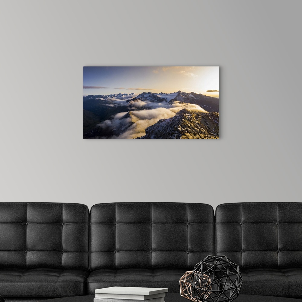 A modern room featuring Aerial panoramic of low clouds covering Corno Tre Signori, Pizzo Tresero and Punta San Matteo pea...