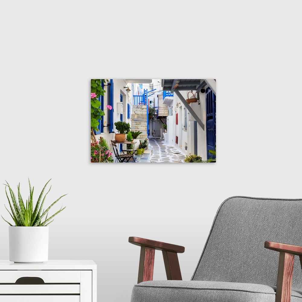 A modern room featuring Narrow street, whitewashed buildings with blue paint work, flowers, Mykonos Town, Mykonos, Cyclad...