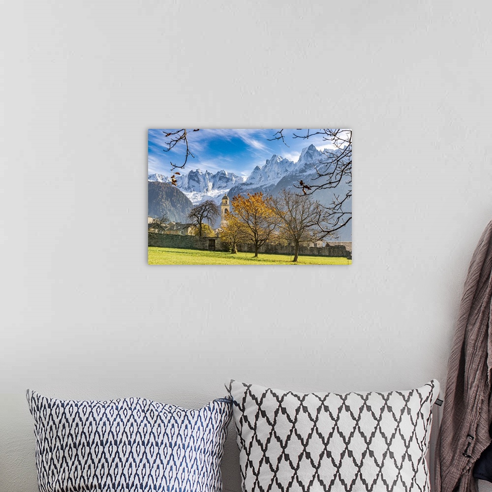 A bohemian room featuring Old church lit by autumn colors with snowcapped Piz Badile and Cengalo in the background, Soglio,...